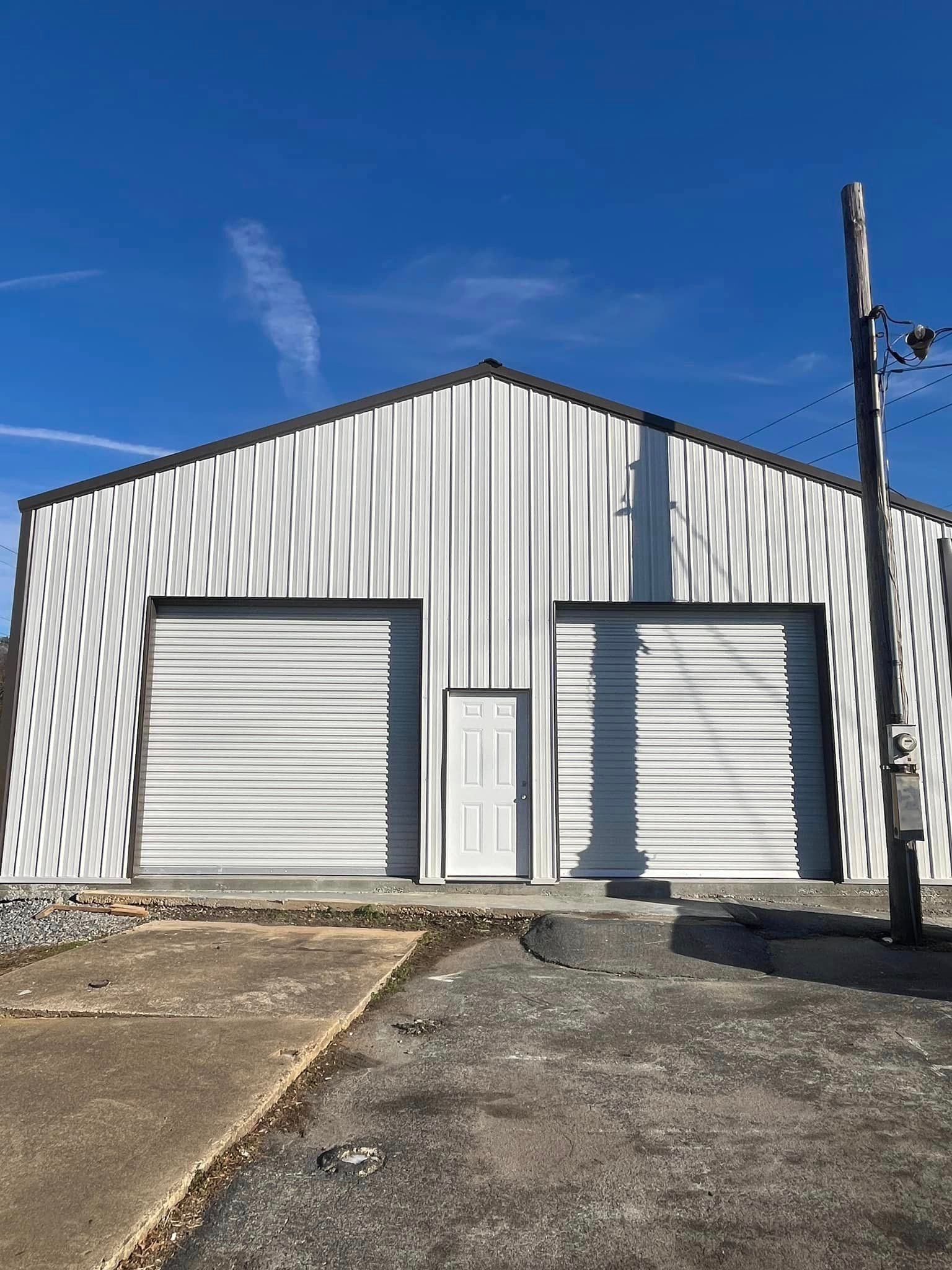 A white building with two garage doors and a fire hydrant in front of it.