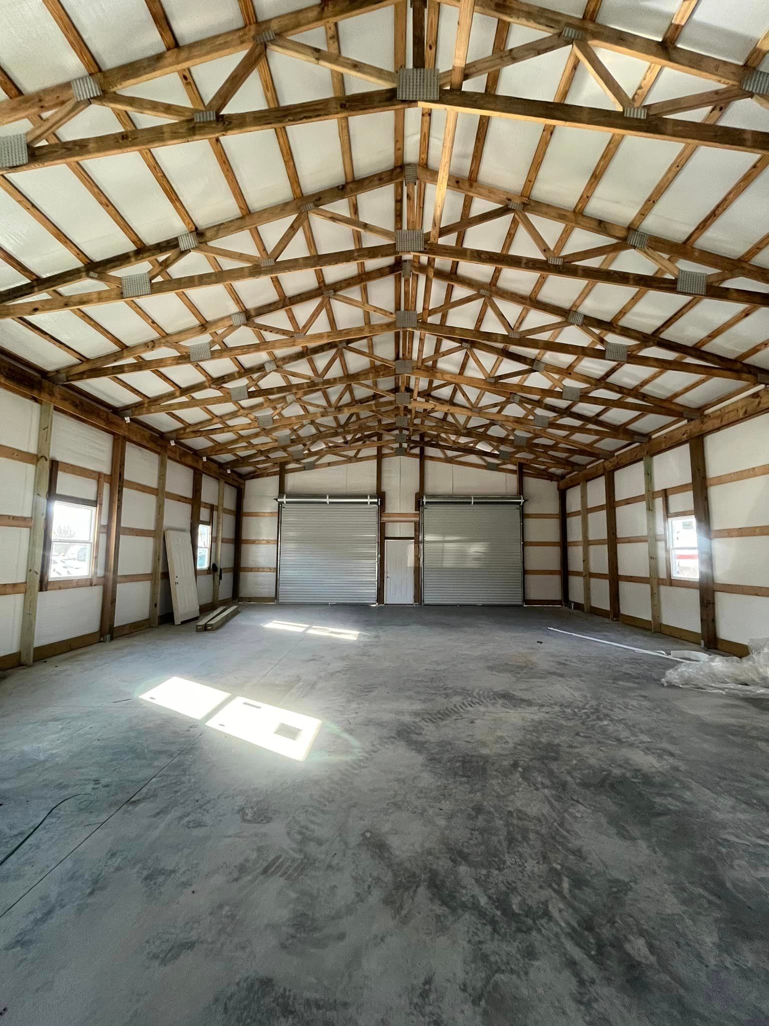 A large empty warehouse with a wooden roof and concrete floor.
