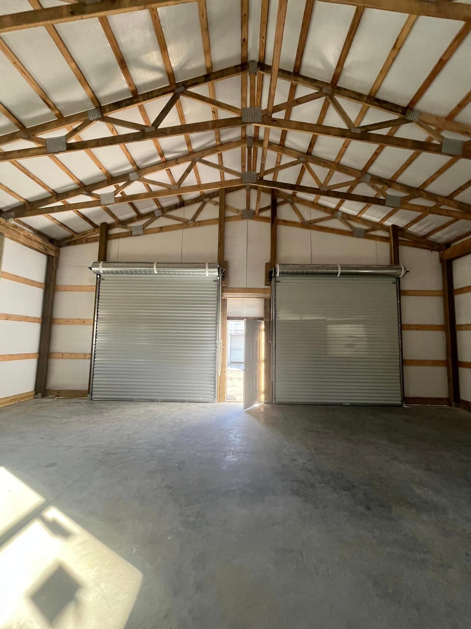 A large empty garage with two garage doors and a wooden roof.