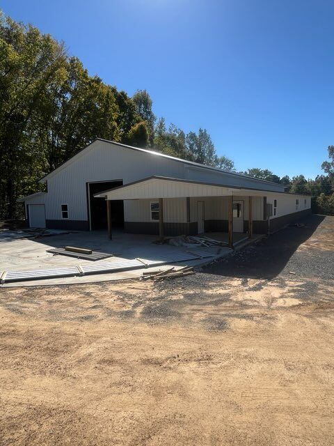 A large barn is sitting in the middle of a dirt field.