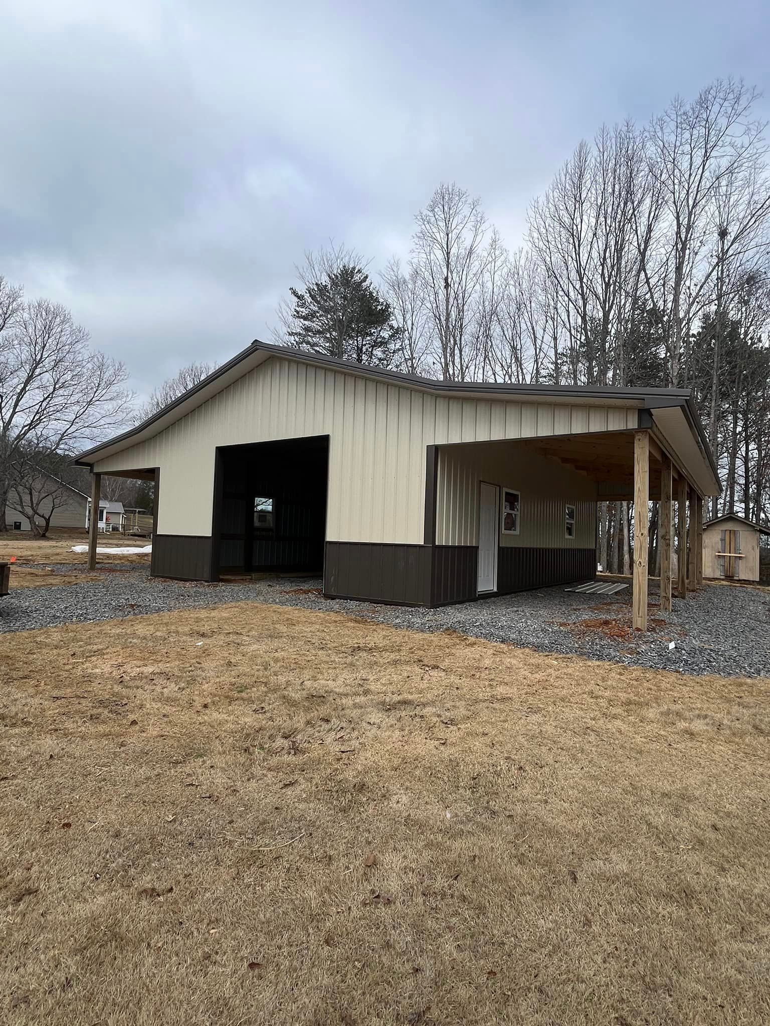 A large barn with a covered porch is sitting in the middle of a field.