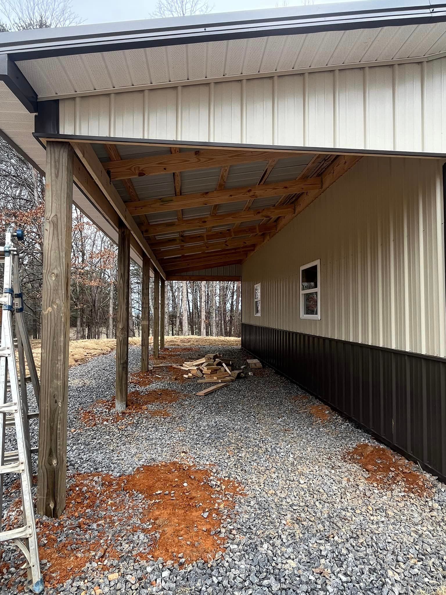 A metal building with a covered porch and a ladder in front of it.