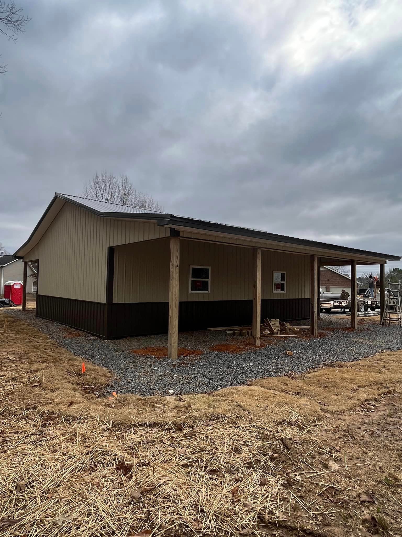 A small house with a porch is sitting in the middle of a field.