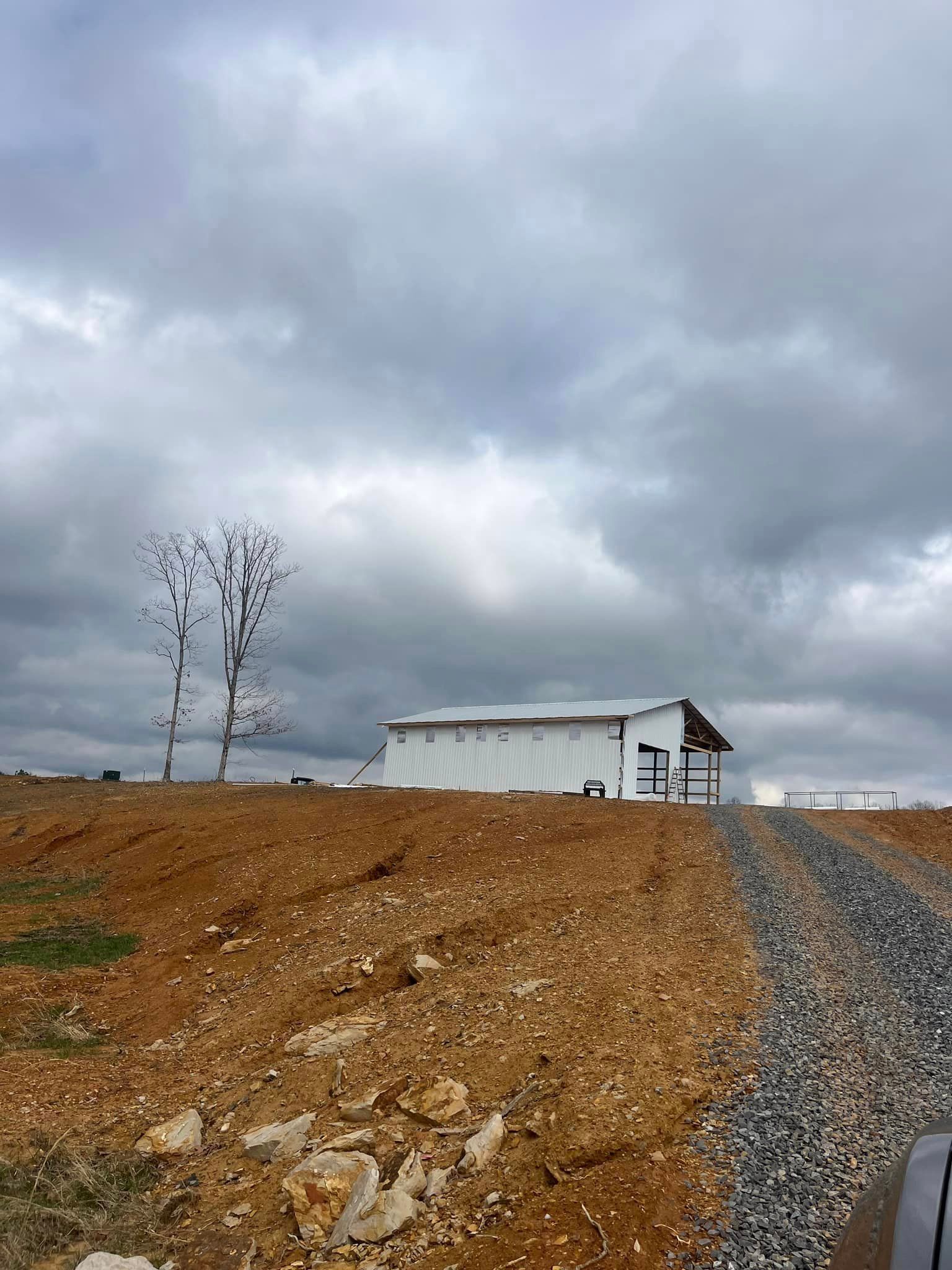 A white building is sitting on top of a dirt hill.