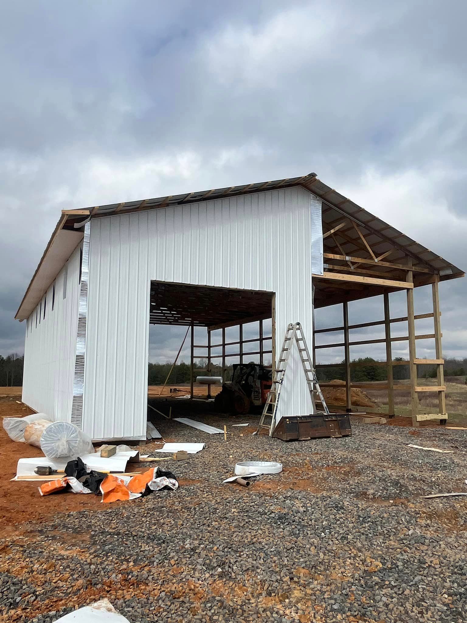 A large white building is being built in the middle of a gravel field.