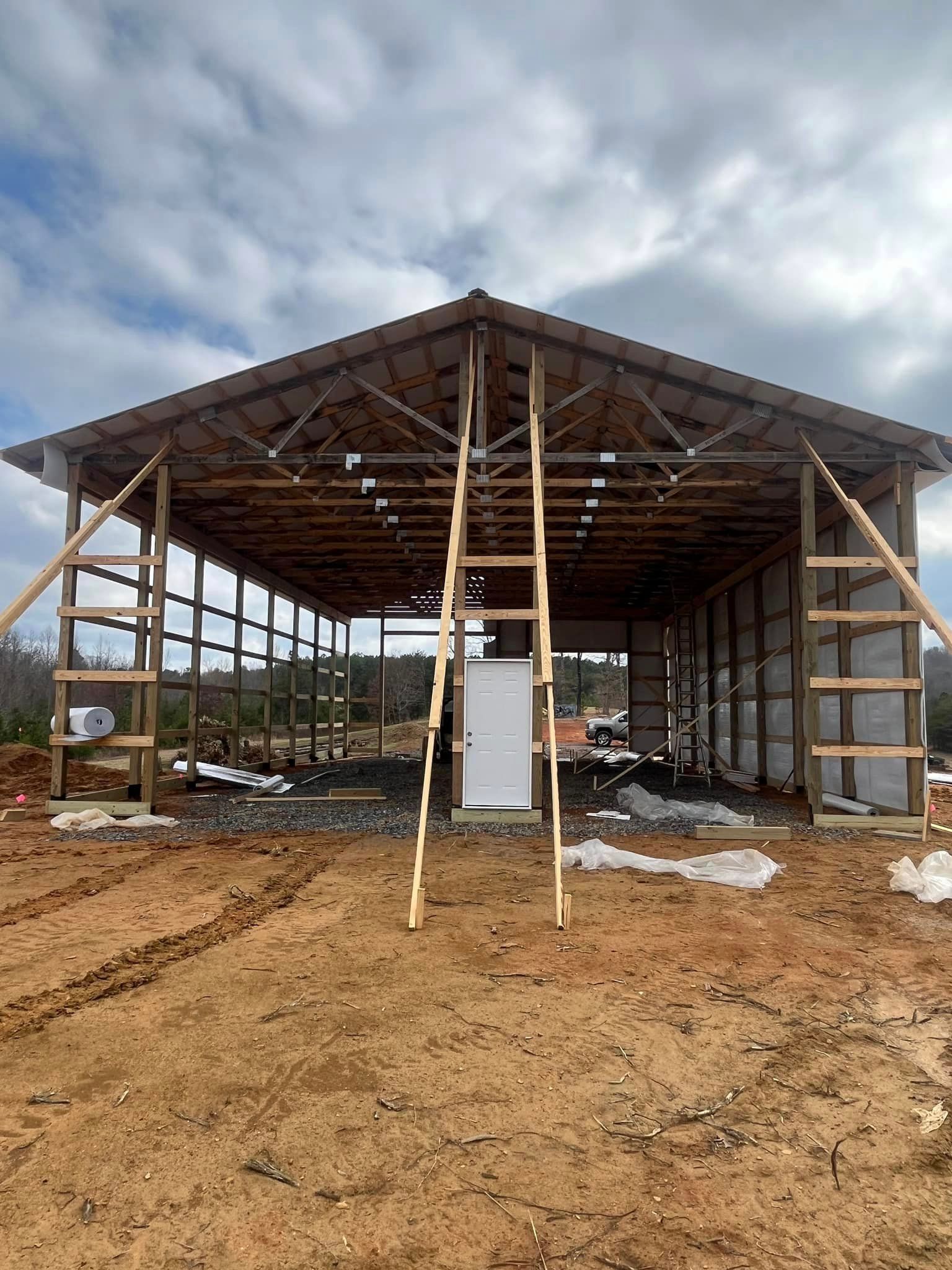 A large wooden building is being built in the middle of a dirt field.