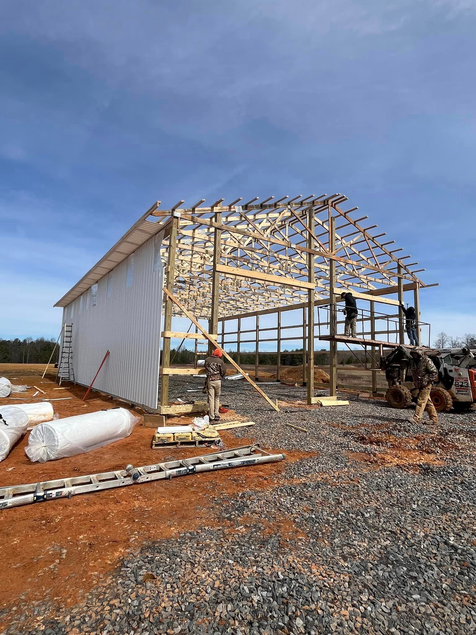 A large wooden building is being built on a dirt field.