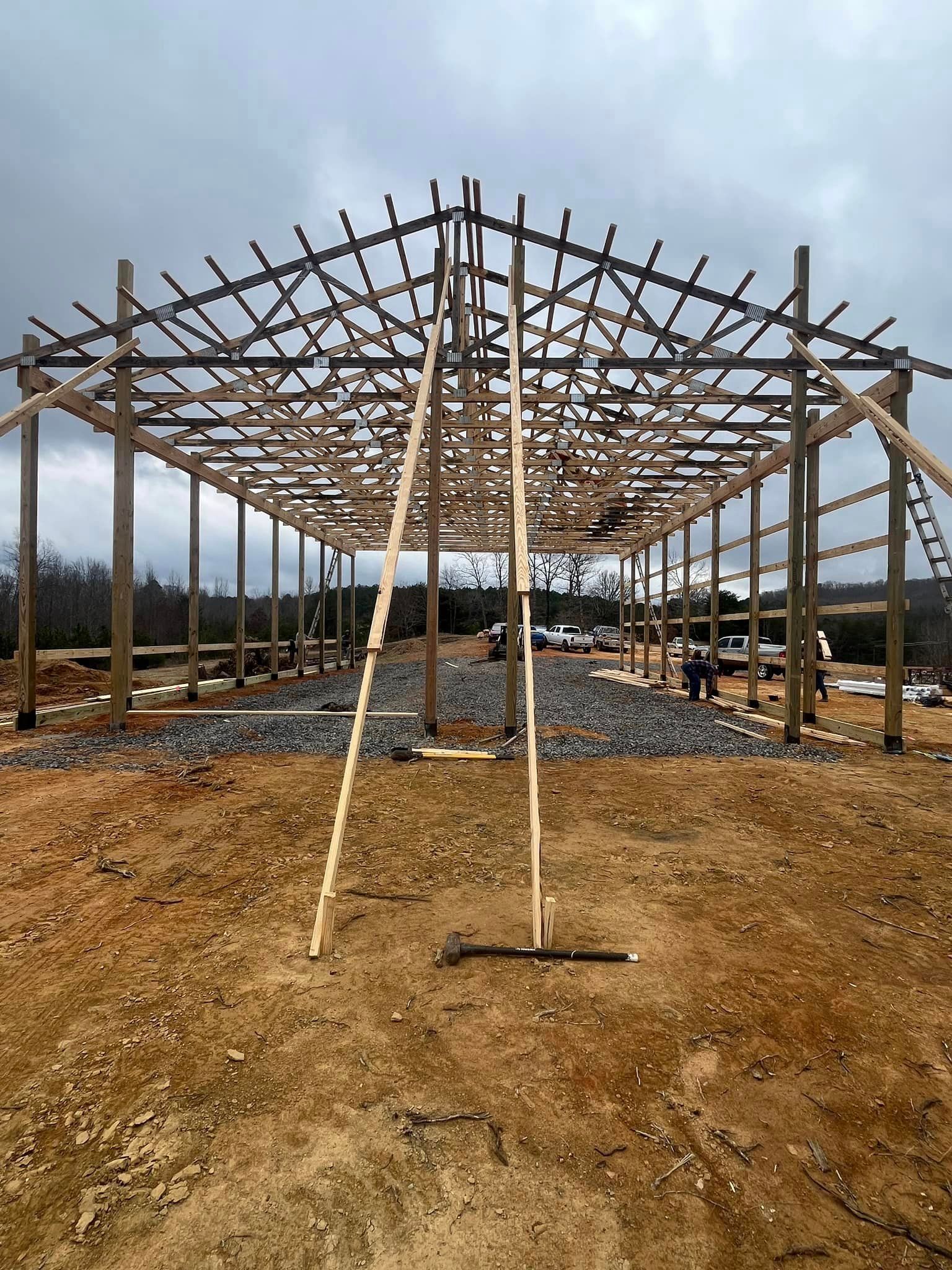 A large wooden structure is being built in a dirt field.