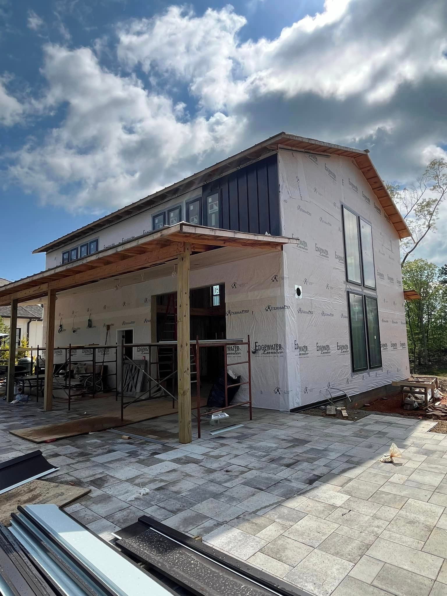 A large white house with a black roof is being built.
