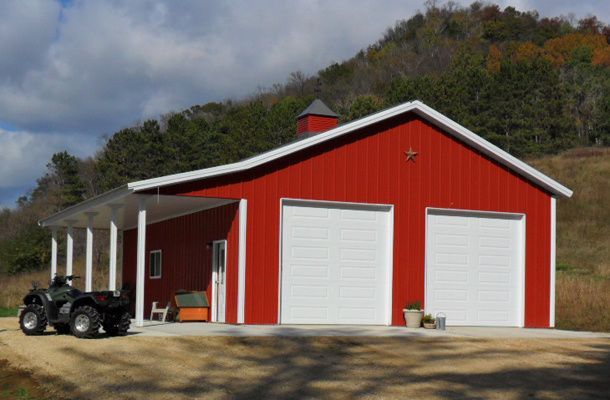 A red and white barn with a four wheeler parked in front of it