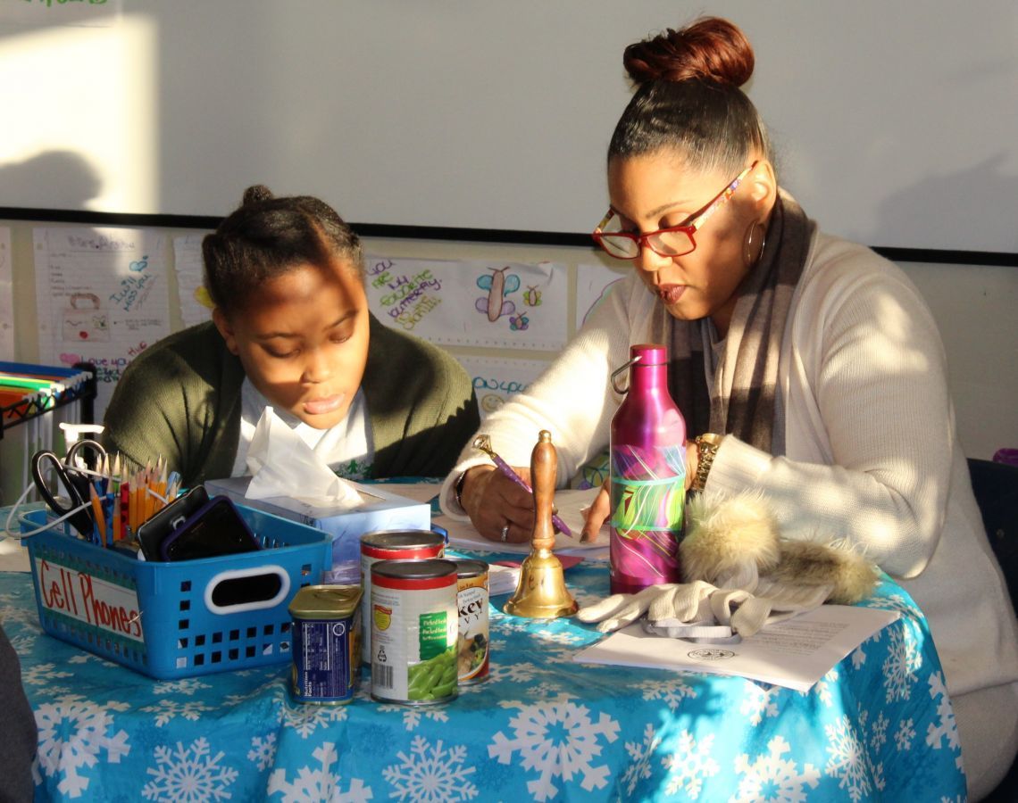 A woman and a child are sitting at a table with a basket that says ' christmas ' on it