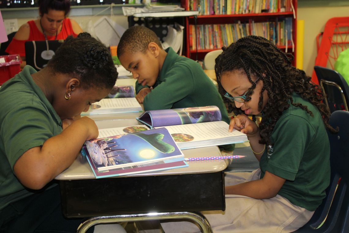 A group of children are sitting at desks reading books