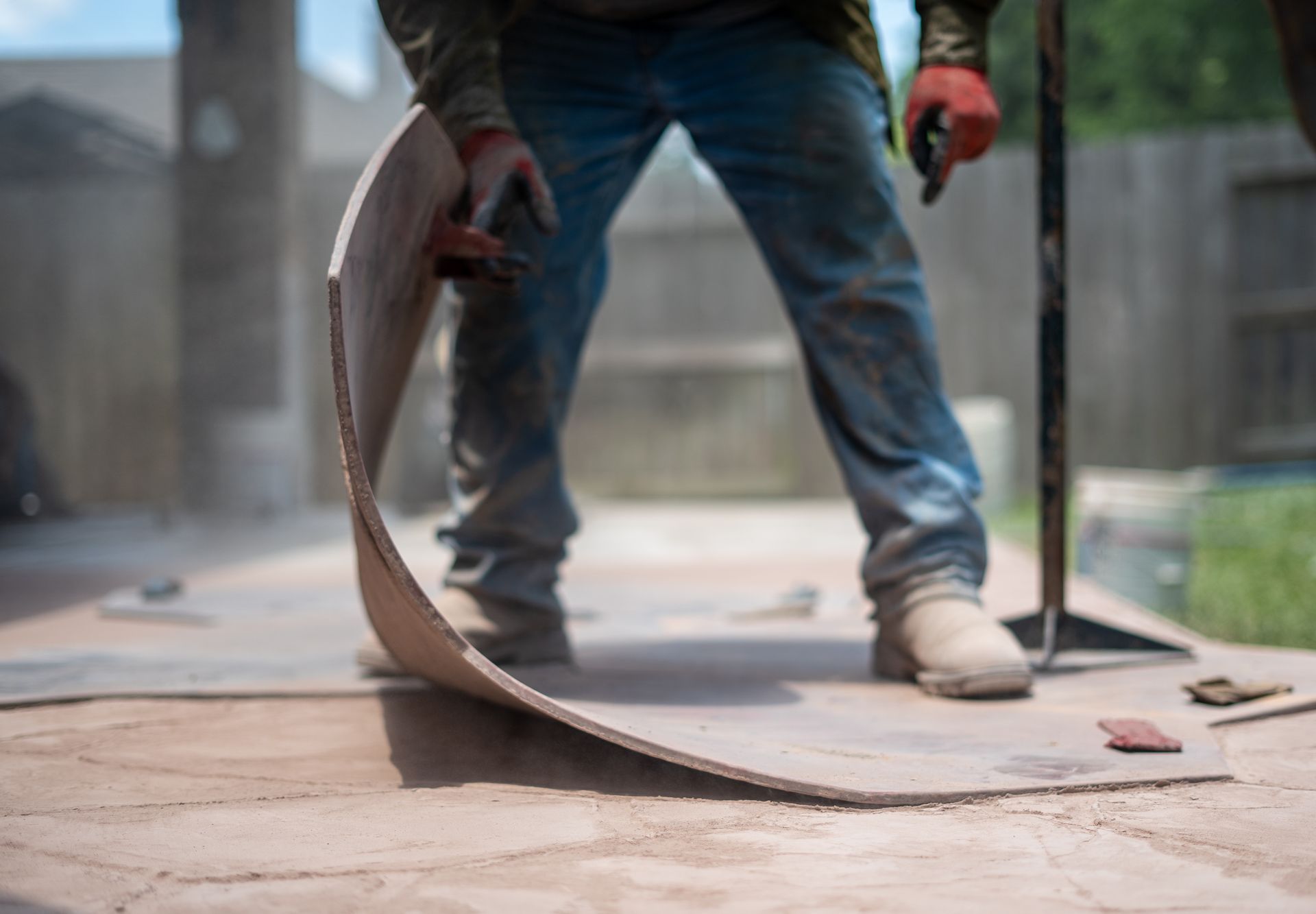 A man is standing on a concrete surface stamping the concrete for a aesthetic design