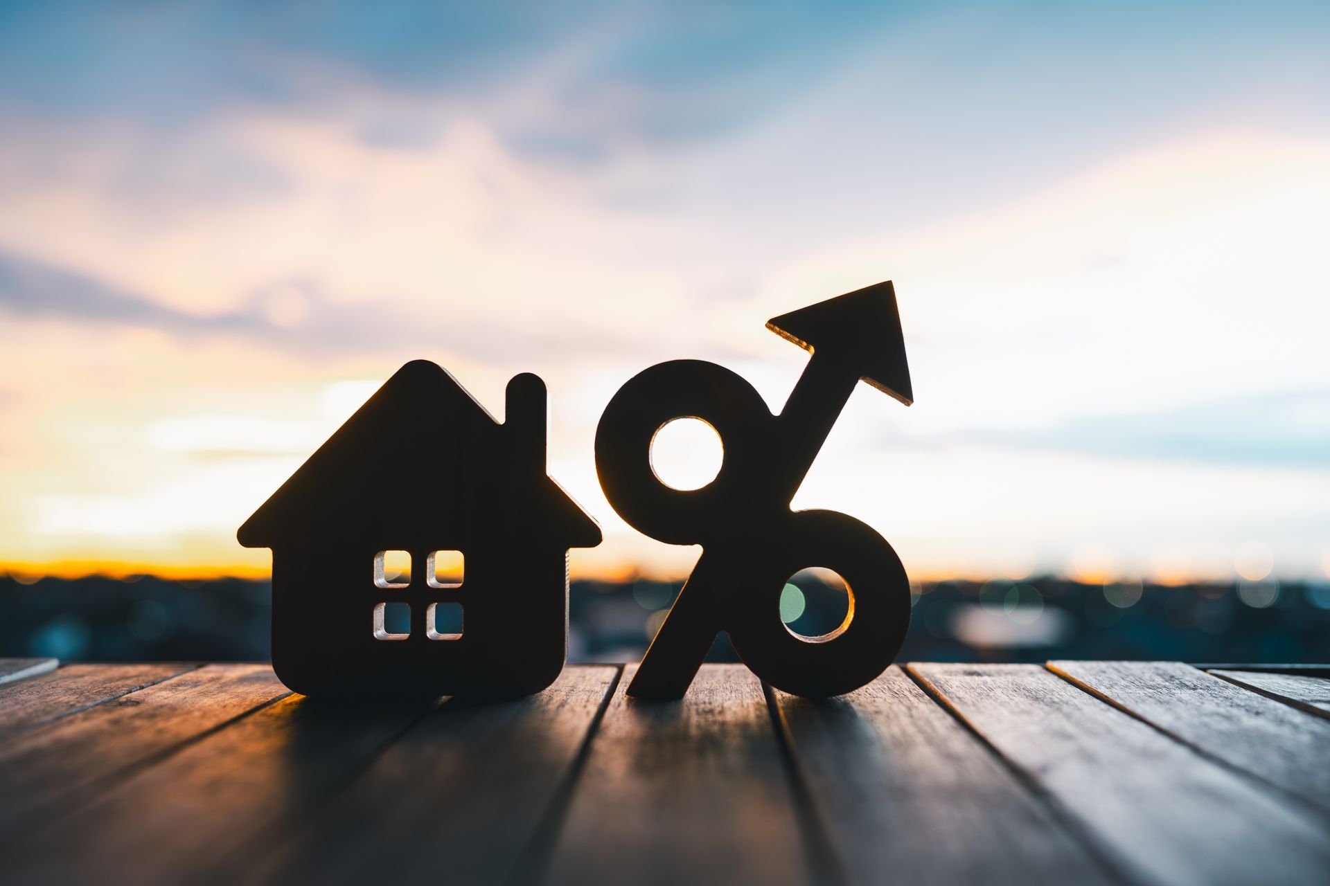 A house and a percent sign are on a wooden table.