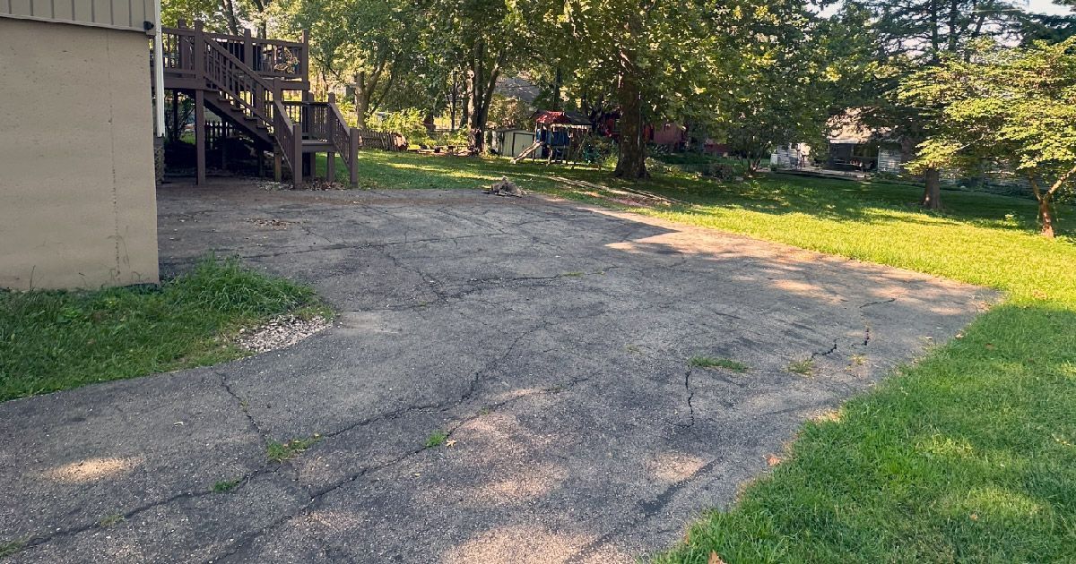 A gravel driveway leading to a house with a wooden deck.