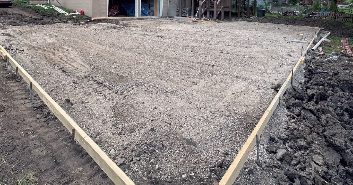 A concrete driveway is being built in front of a house.