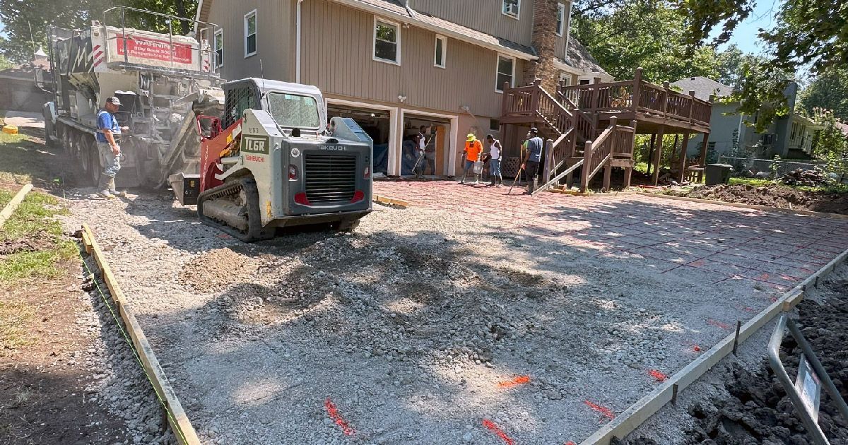 A group of people are working on a driveway in front of a house.