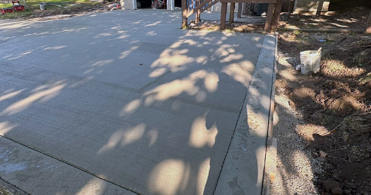 A shadow of a tree is cast on a concrete driveway.