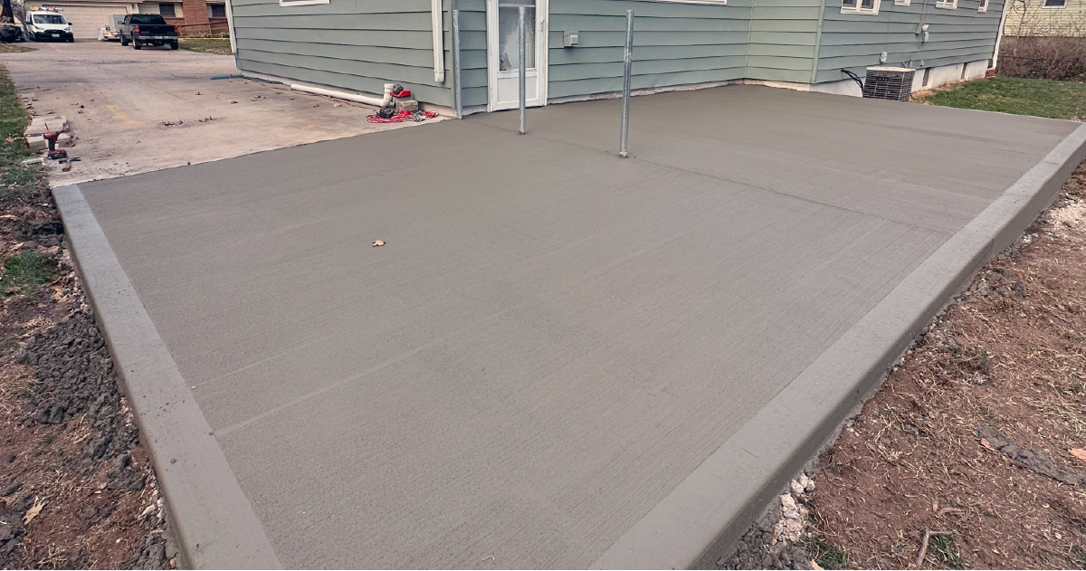 A concrete patio is being built in front of a house.