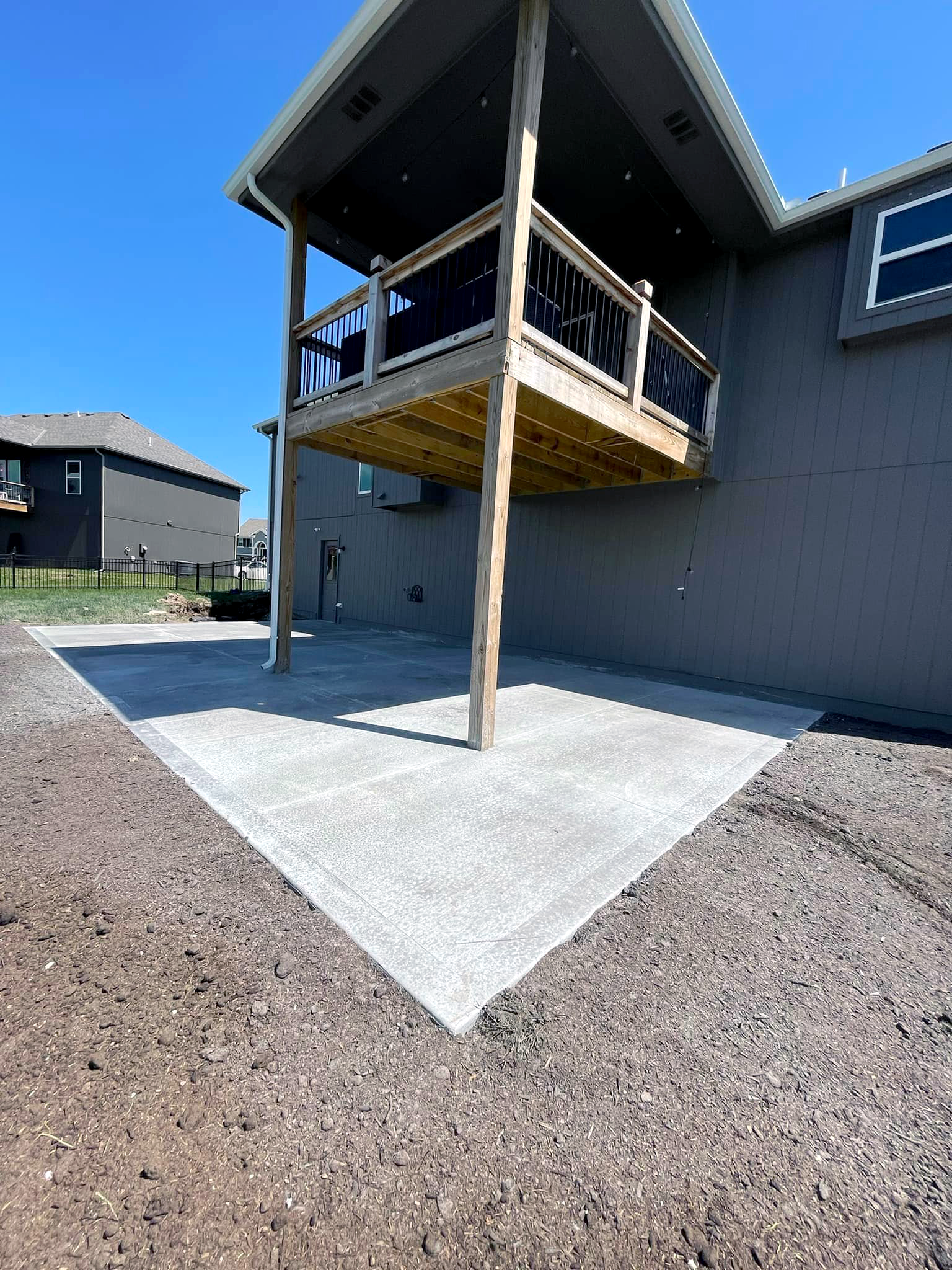 A house with a concrete patio and a wooden deck.