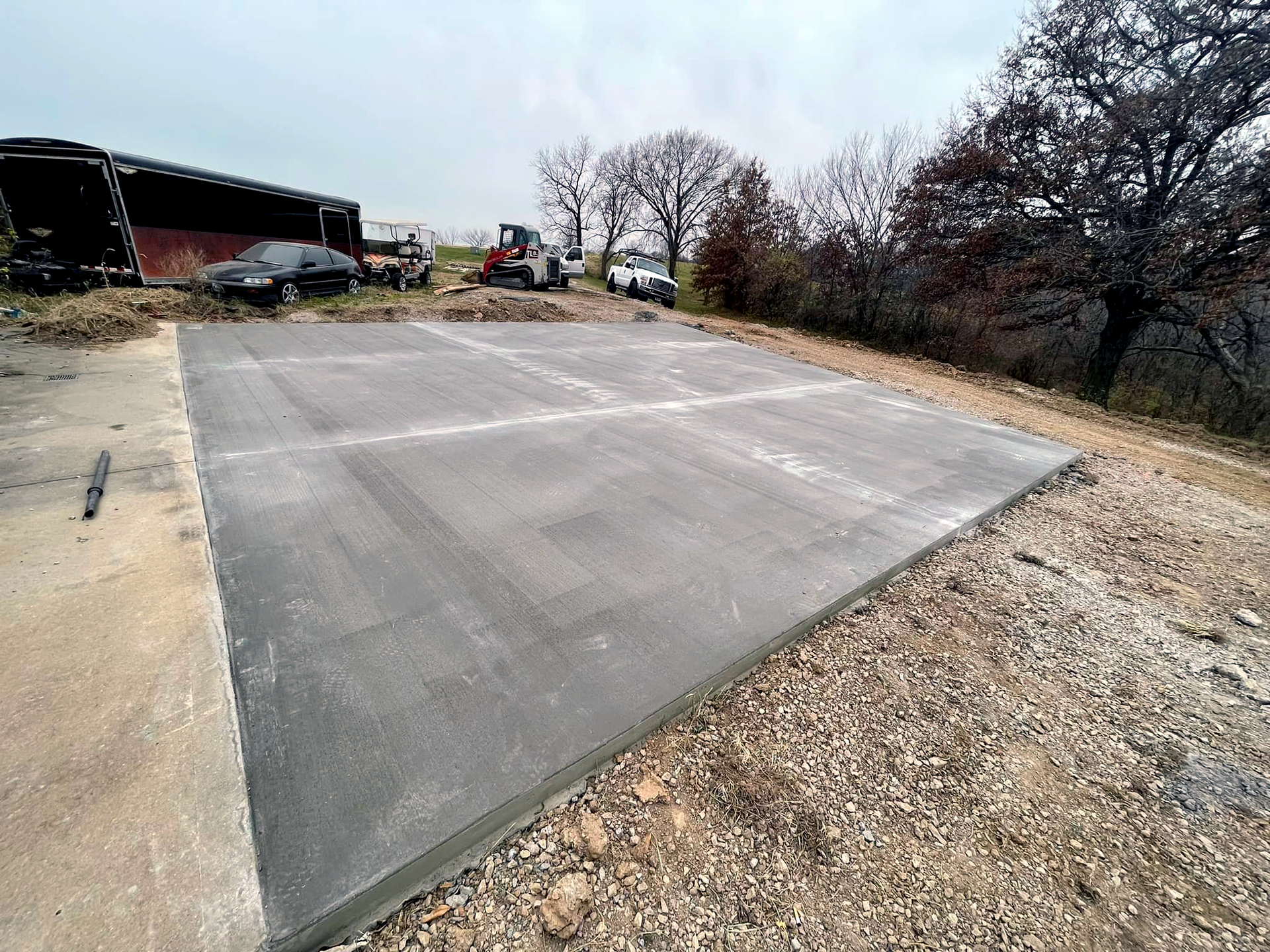 A concrete driveway is being built next to a dirt road.
