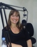 June sitting in front of a microphone and smiling.