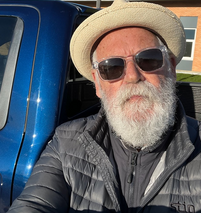 Testimonial of man with a beard wearing a hat and sunglasses is sitting in the back of a truck.