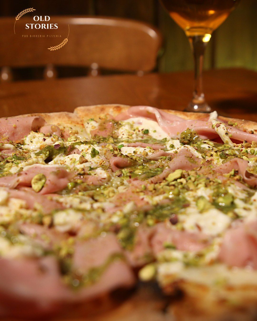 Una pizza è appoggiata su un tavolo accanto a un bicchiere di vino.