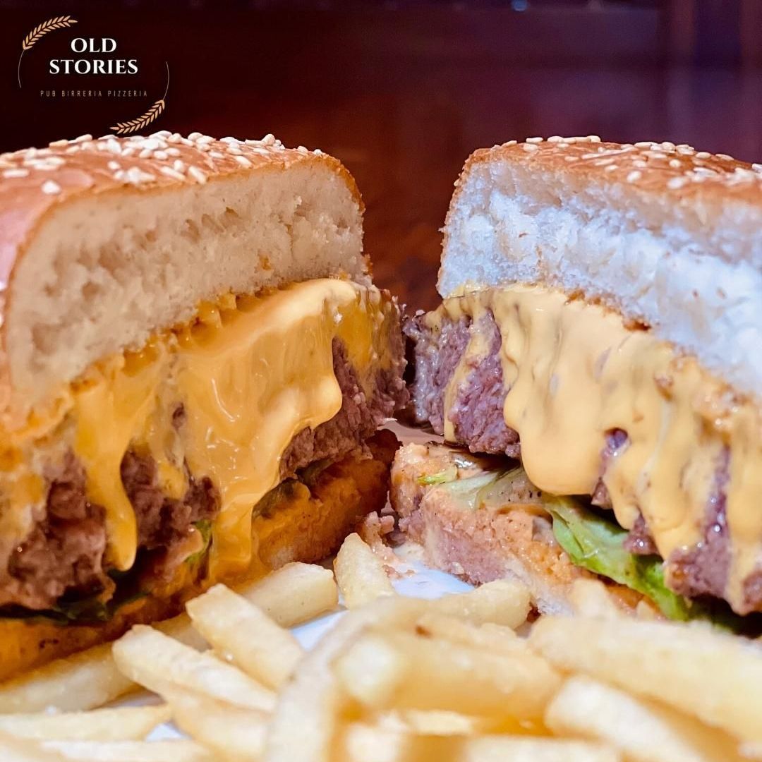 Un hamburger viene tagliato a metà e adagiato su un piatto con patatine fritte