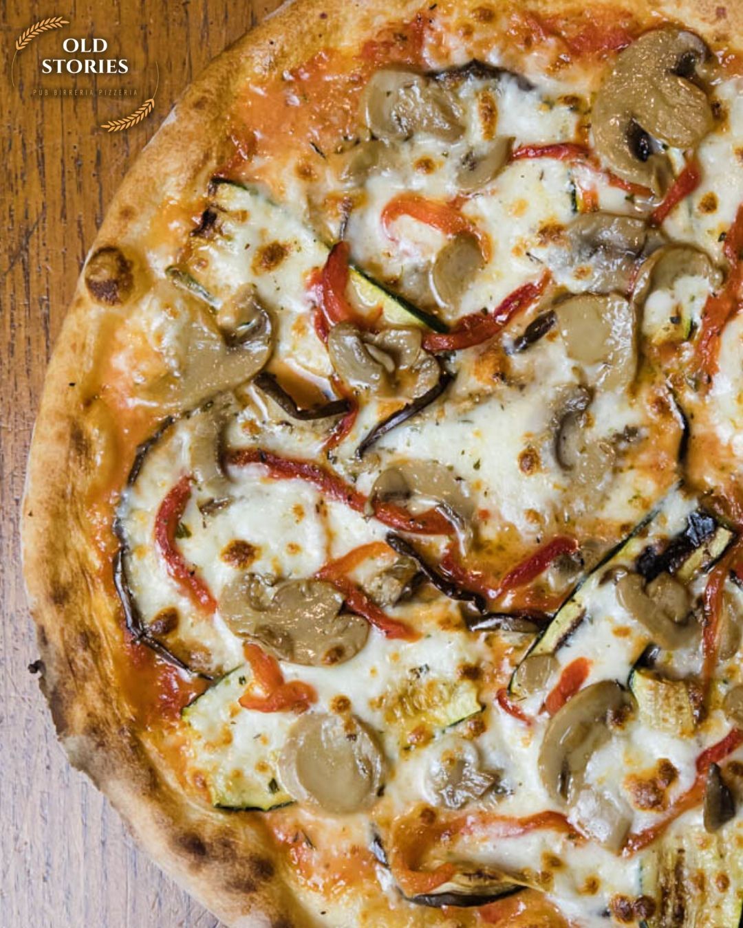 Una pizza con funghi, peperoni e zucchine su un tavolo di legno