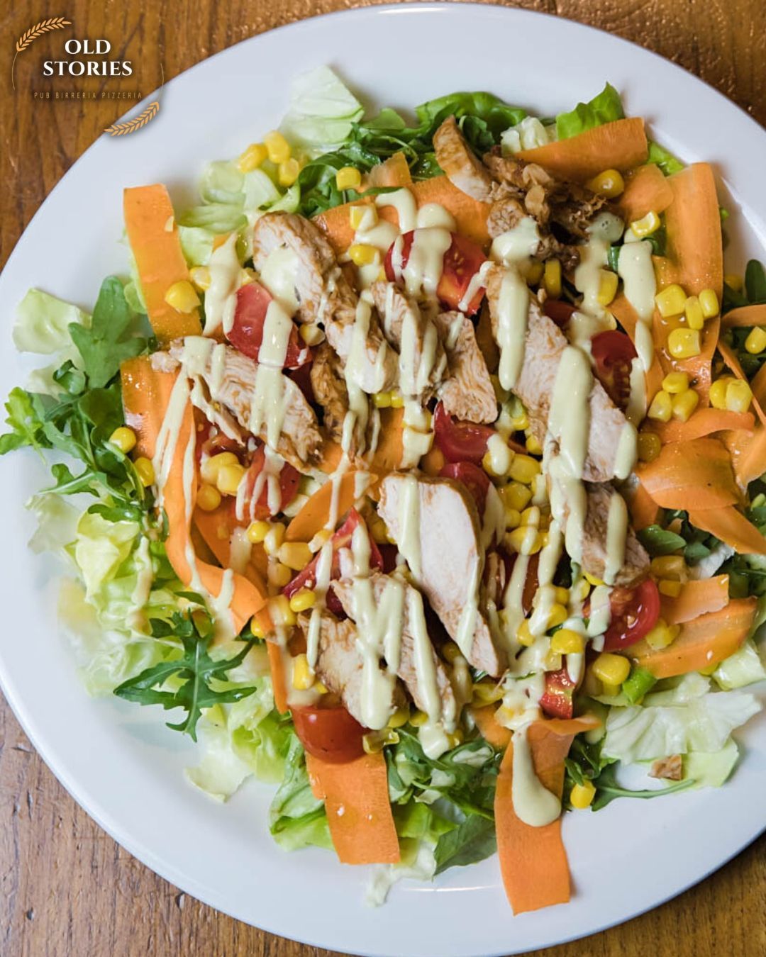 Un'insalata con pollo, carote e mais su un piatto bianco