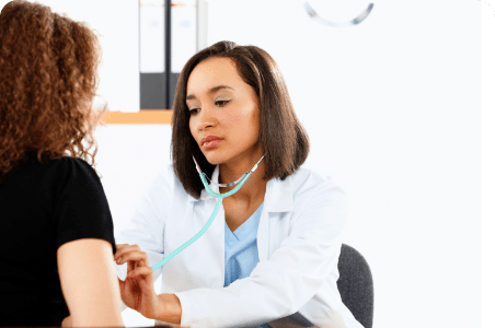 Doctor examining a patient with a stethoscope in a clinical setting.