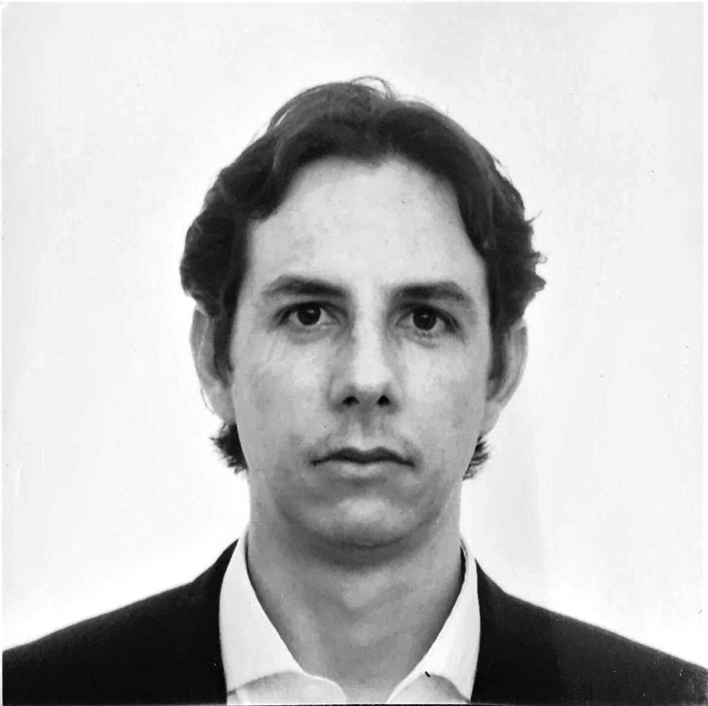 Una fotografía en blanco y negro de un hombre con traje y camisa blanca.