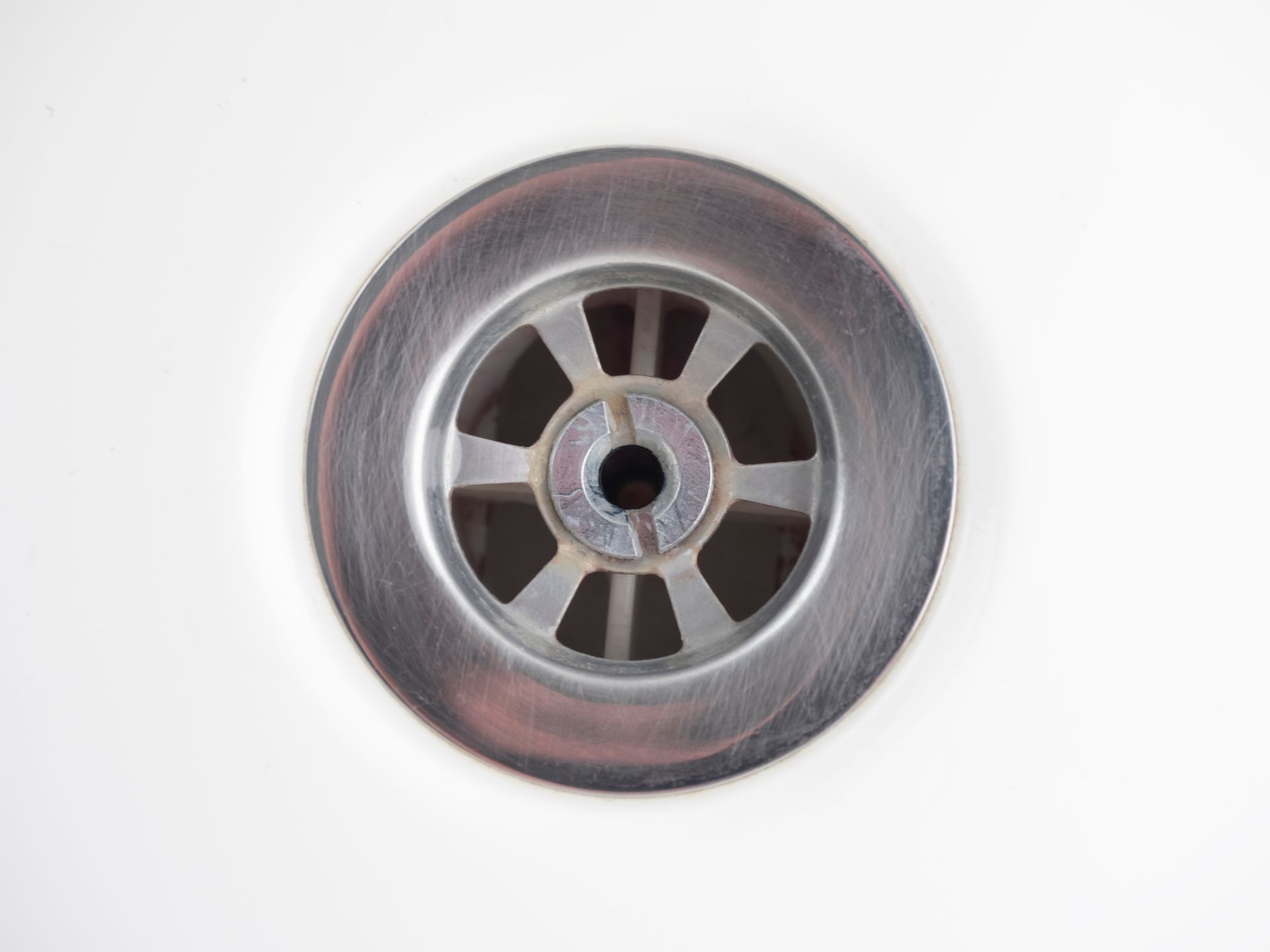 Metal drain centered in a clean, stainless steel sink basin.