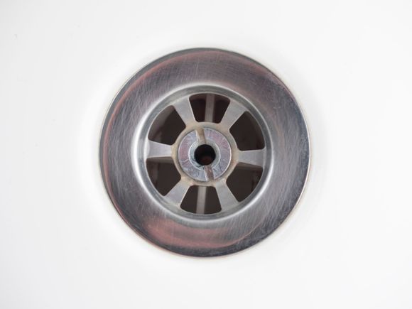 Metal drain centered in a clean, stainless steel sink basin.