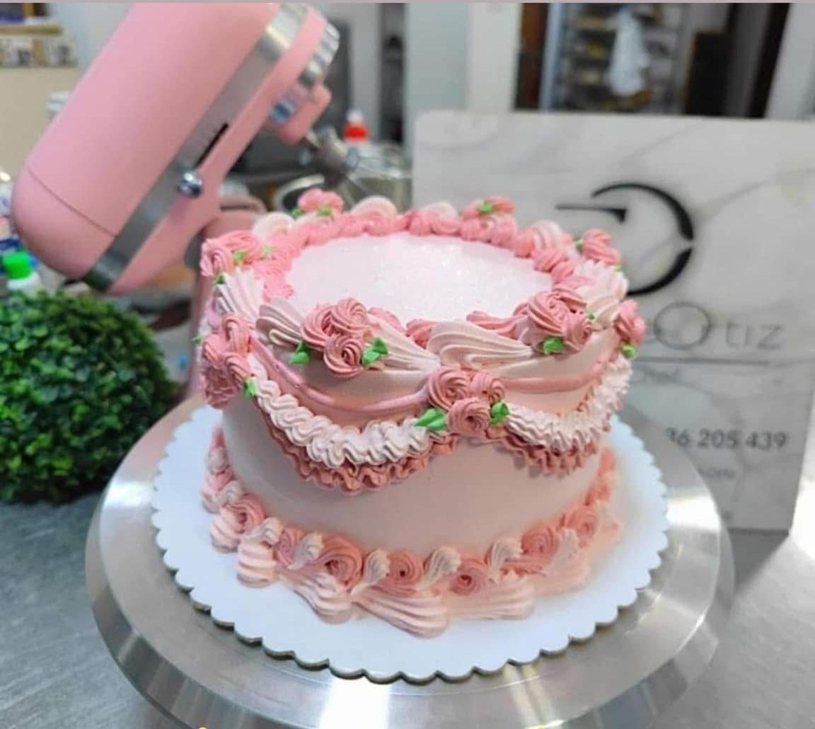 Un pastel con glaseado rosa y flores encima.
