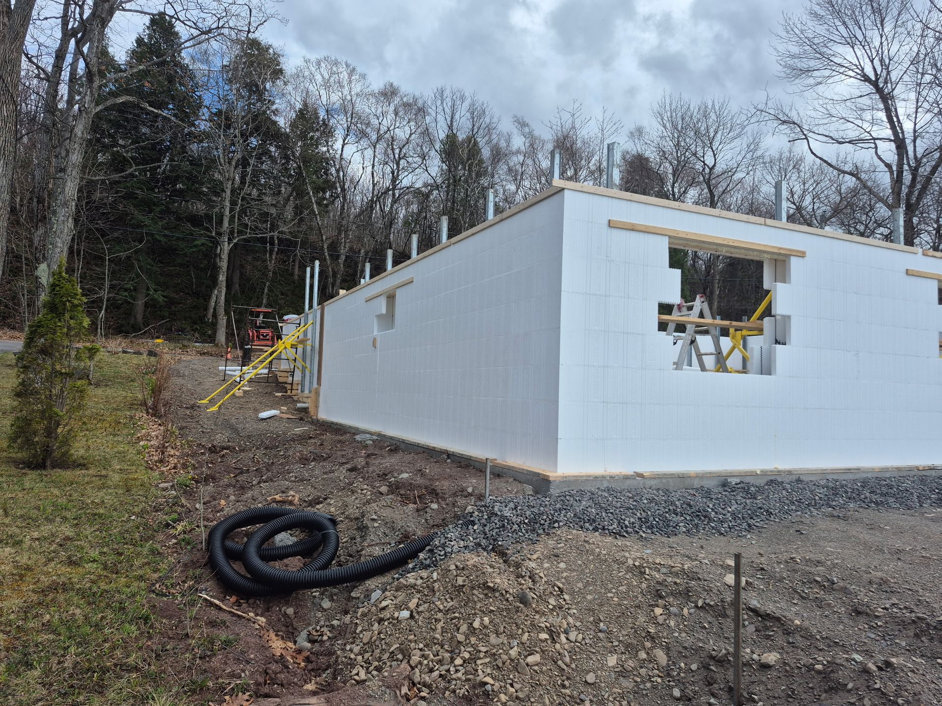 Une maison blanche est en construction au milieu d'une forêt.