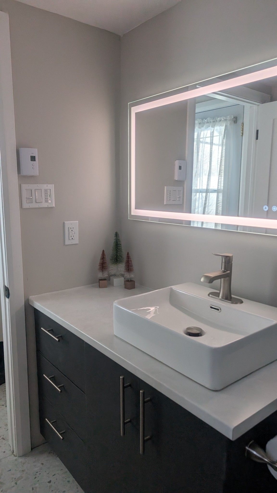 Une salle de bain avec un lavabo, un miroir et des armoires.