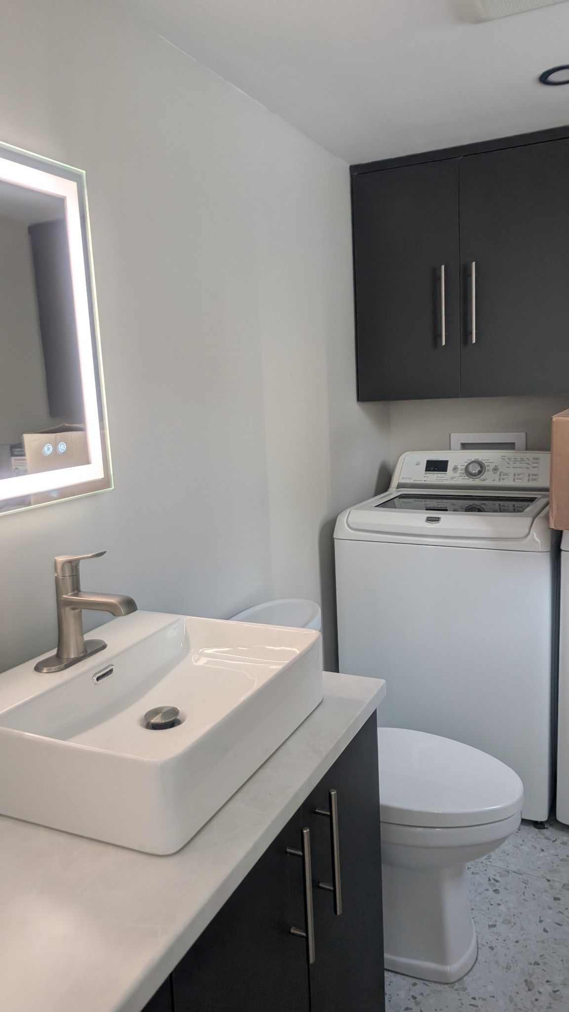 Une salle de bain avec lavabo, toilettes, laveuse et sécheuse.