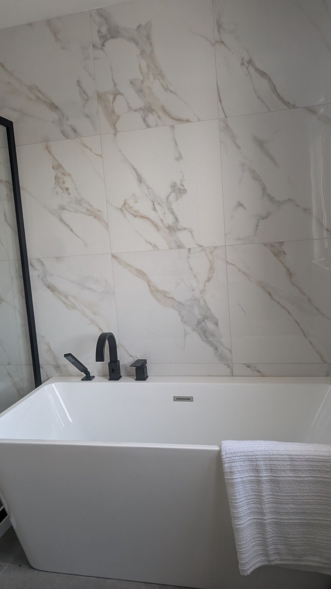 Une salle de bain avec baignoire et un mur en marbre.