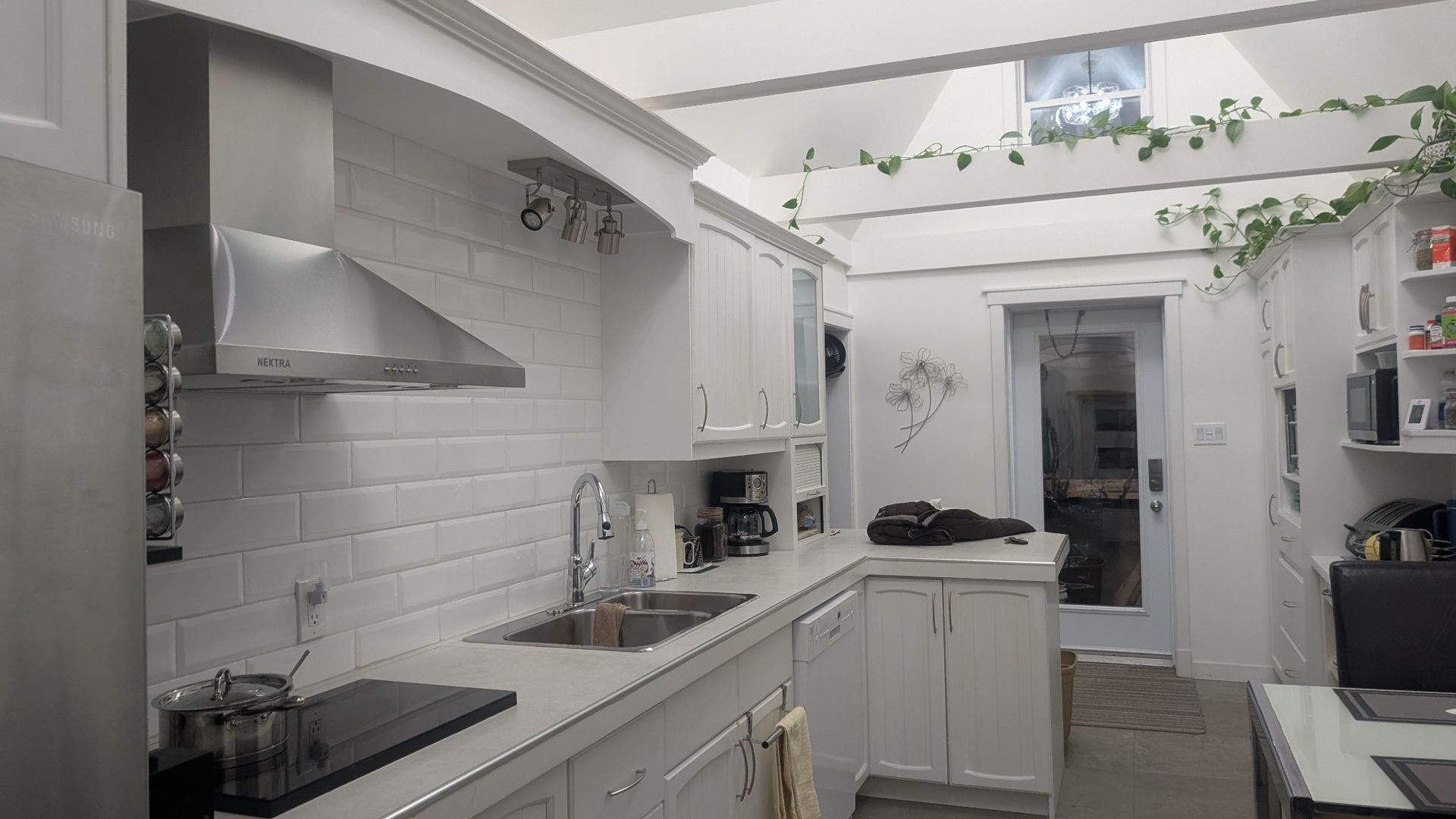 Une cuisine avec des armoires blanches, un évier, une cuisinière et un ordinateur portable sur le comptoir.