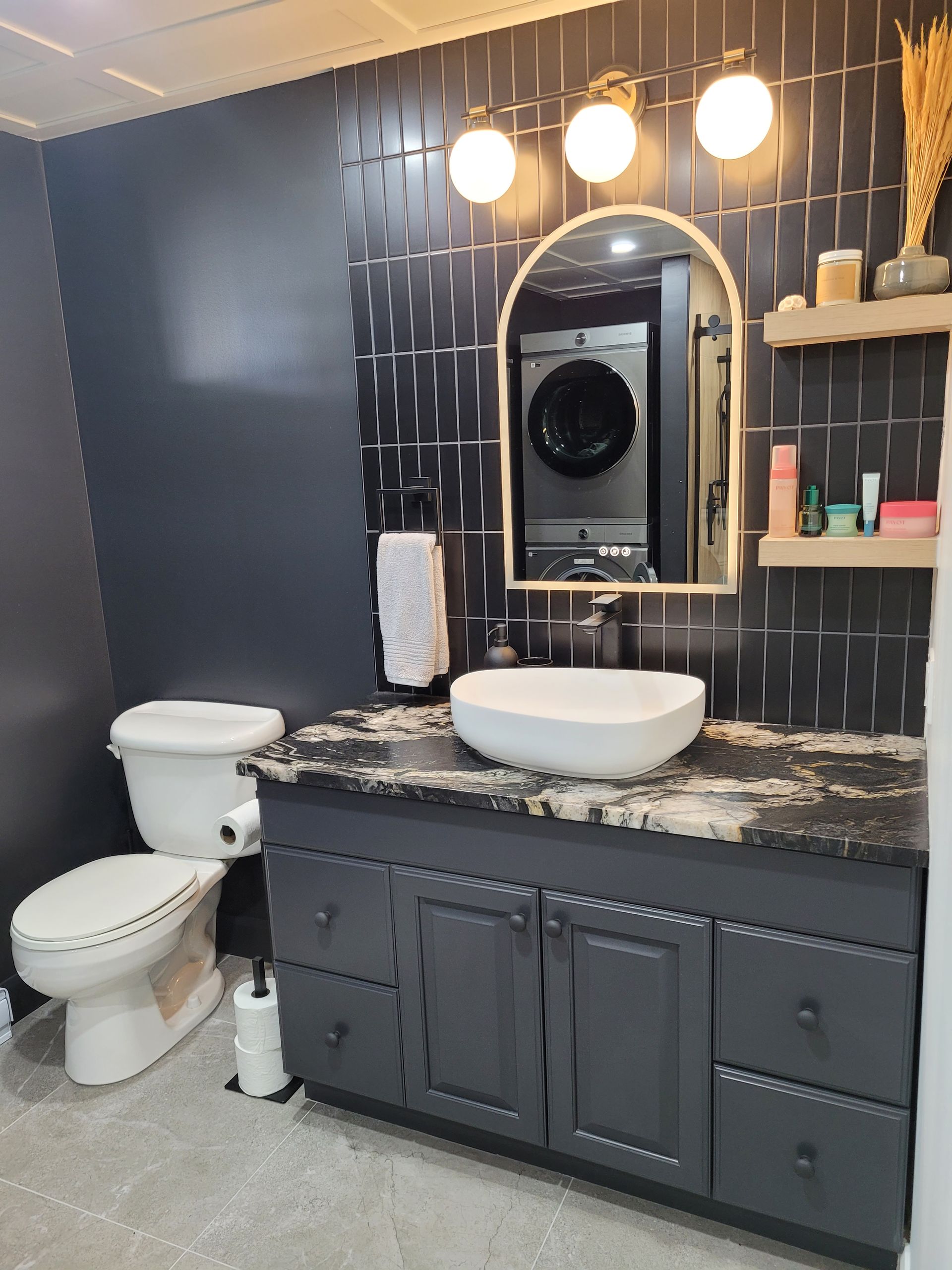 Une salle de bain avec baignoire, douche et porte de douche noire.