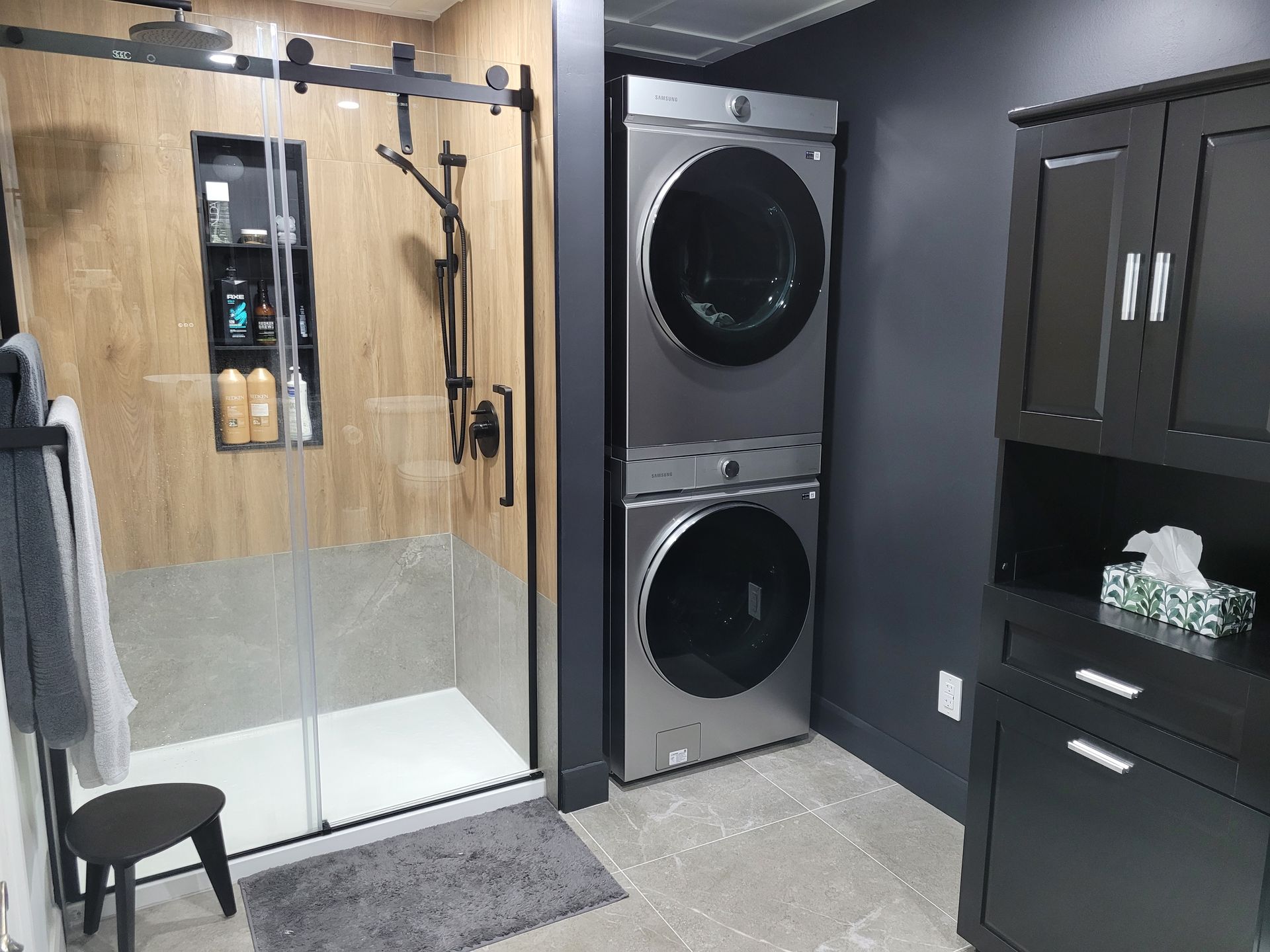 Une salle de bain avec une laveuse et une sécheuse empilées l'une sur l'autre.