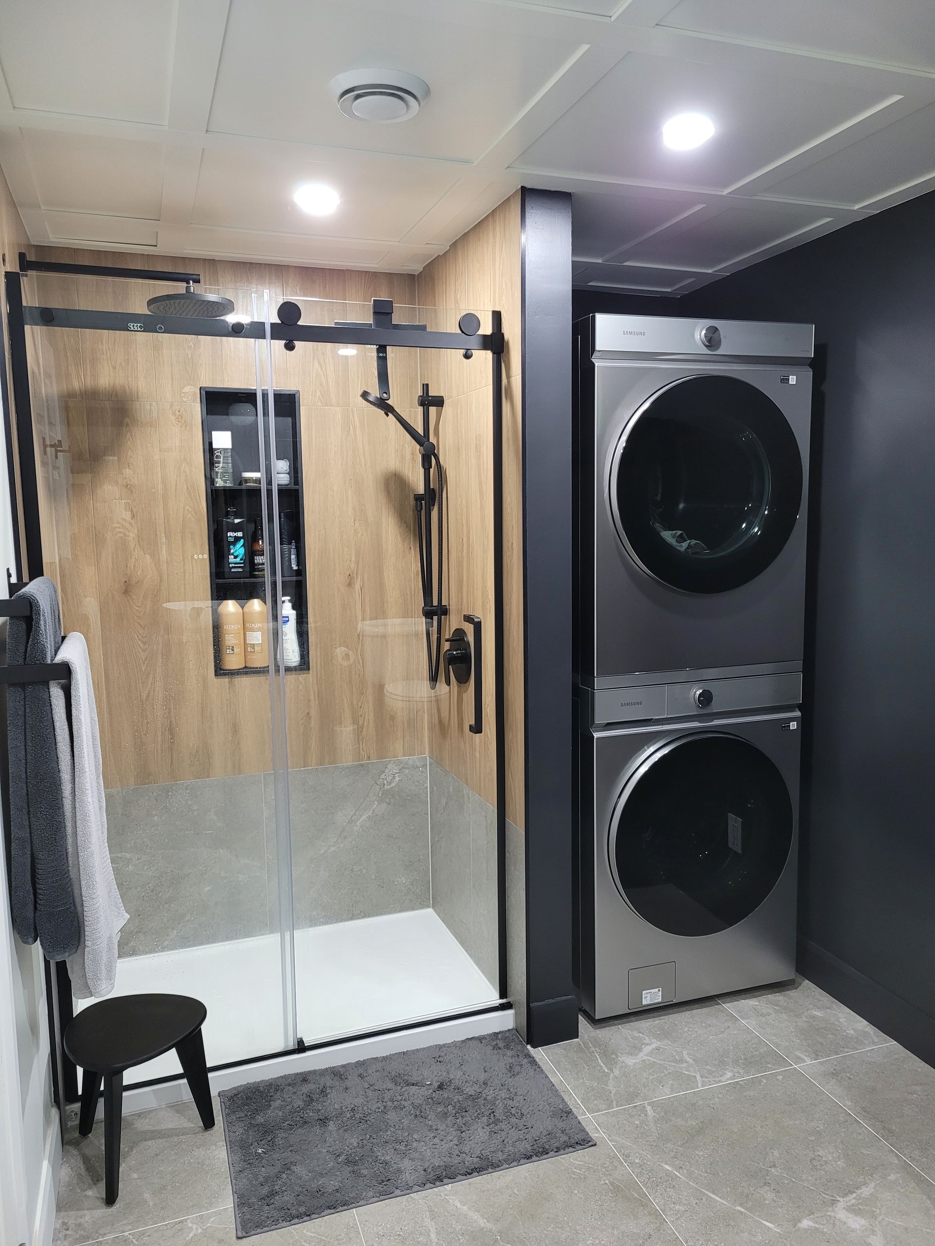 Une salle de bain avec une laveuse et une sécheuse empilées l'une sur l'autre.