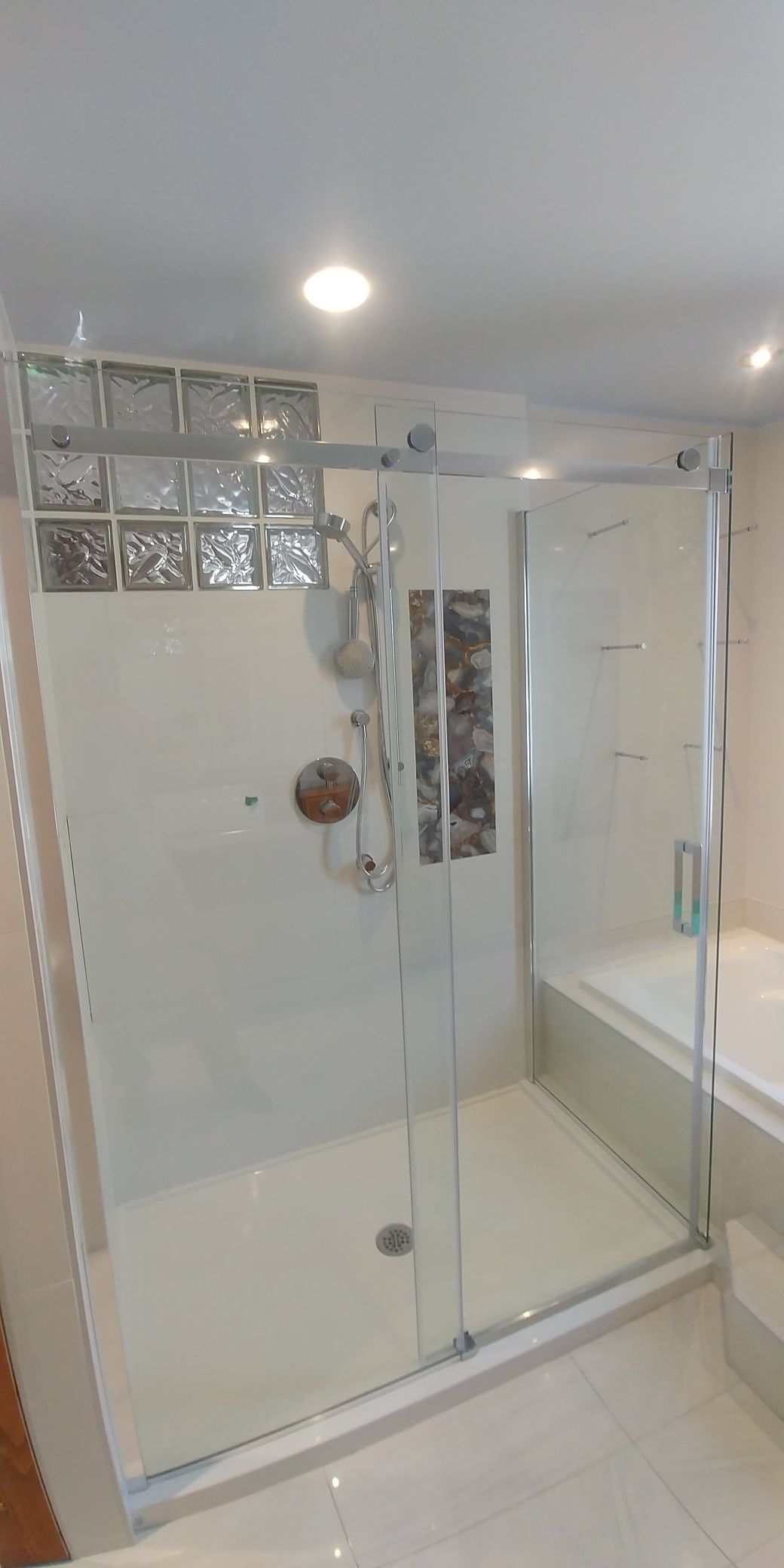 Une salle de bain avec baignoire, douche et porte de douche noire.