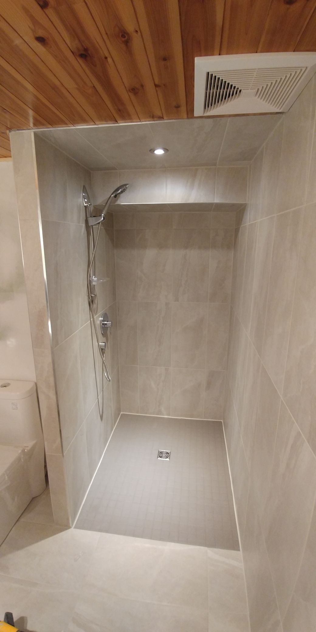 Une salle de bain avec douche à l'italienne et plafond en bois.