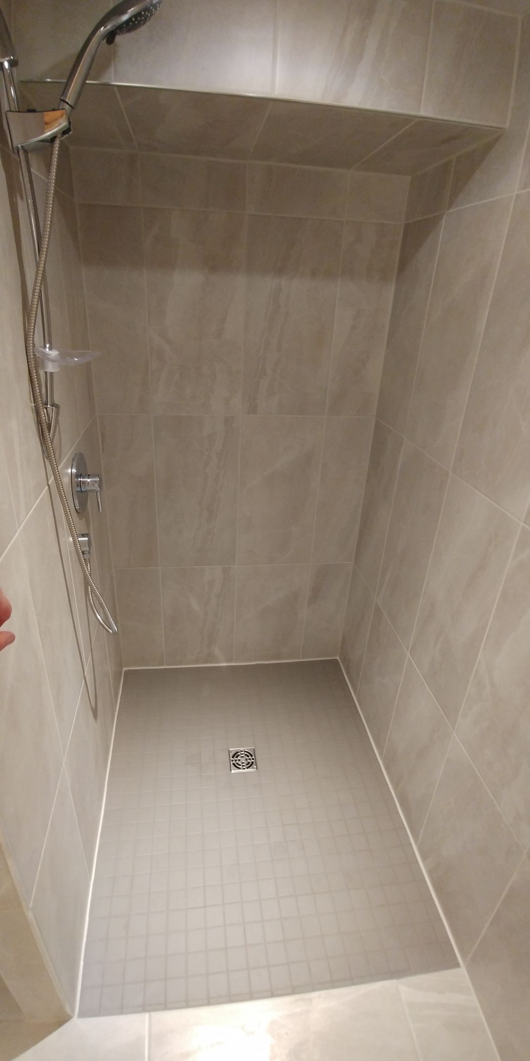 Une personne est debout dans une douche avec une pomme de douche.