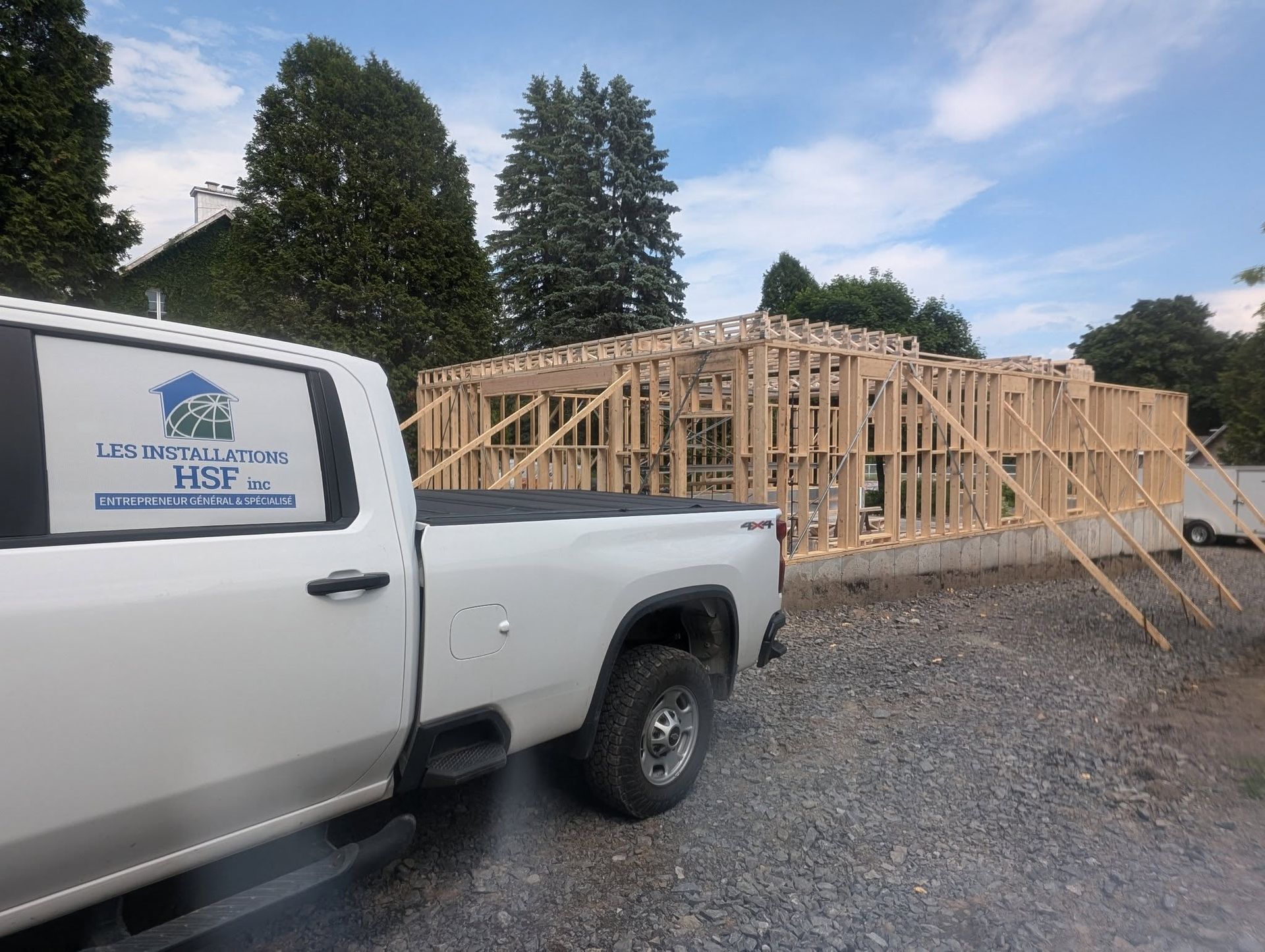 Un camion blanc est garé devant une maison en construction