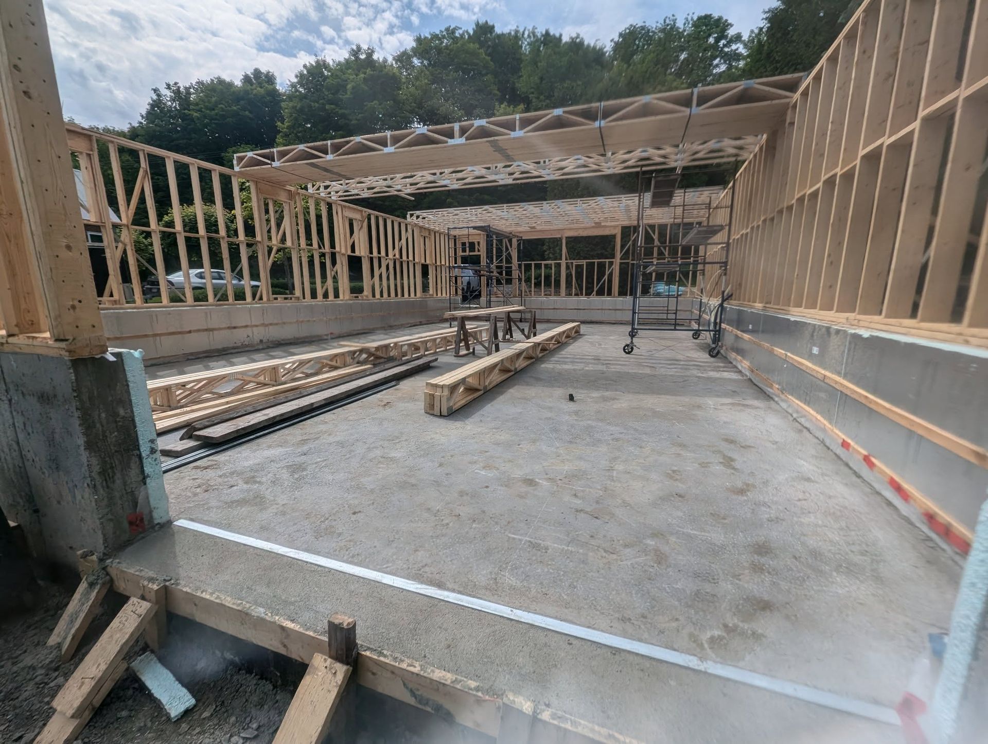 Un bâtiment est en cours de construction avec des poutres en bois et un sol en béton.
