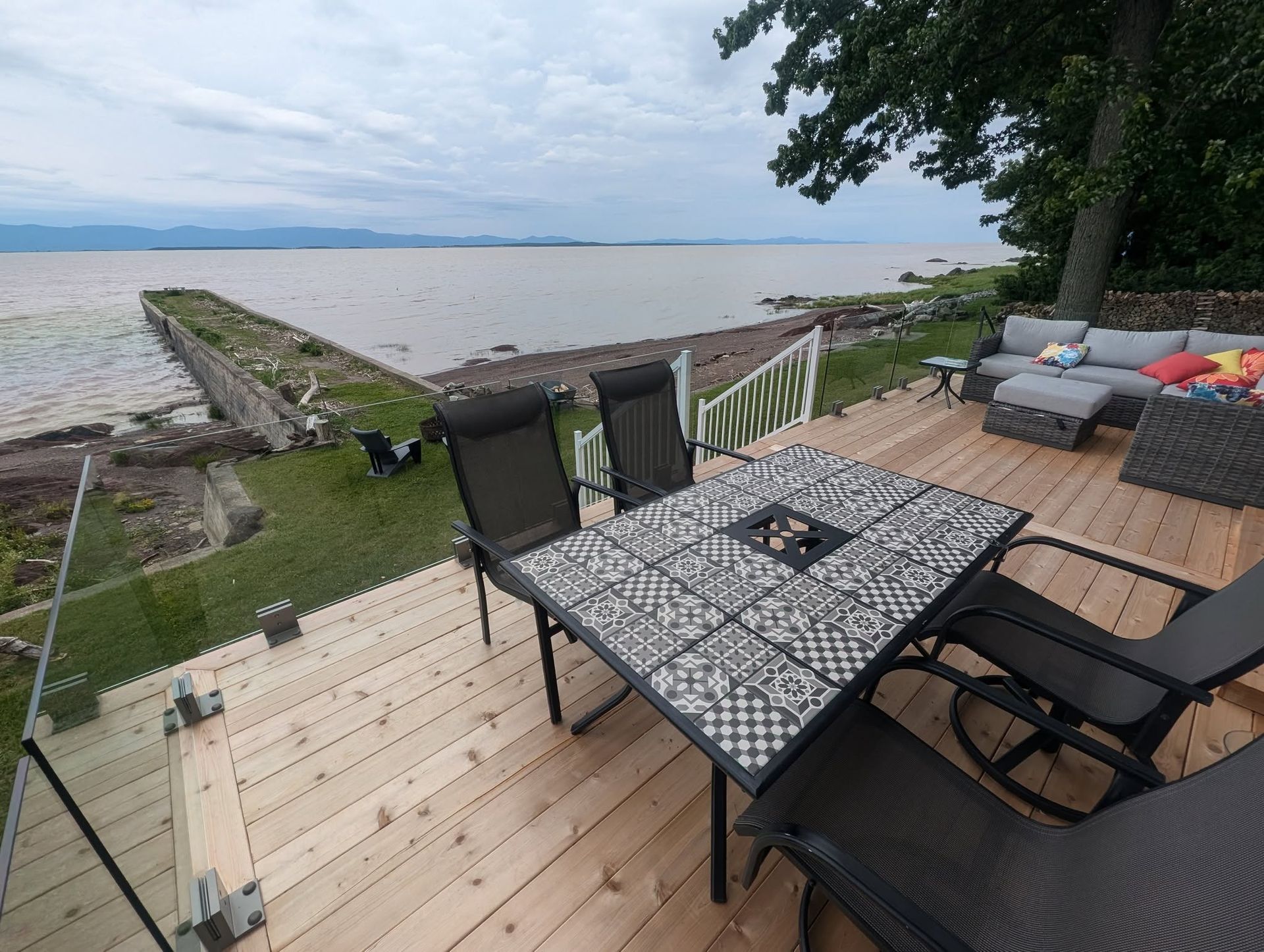 Une terrasse en bois avec une table et des chaises donnant sur l'océan.